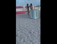 Two women walk and turn beach tent