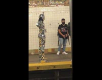 Guy in silver shine outfit adjusts clothes at subway 