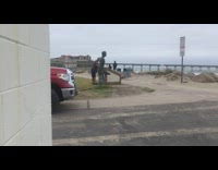 homeless man throws things at statue at beach