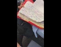 Collab Subway Creatures - Guy writes in red notebook folder full of numbers on subway train