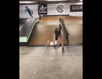 Girl skateboards up ramp, trips and face plants in indoor skate park