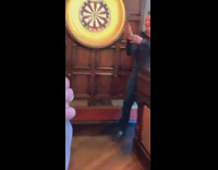 Guy throws dart at hand on dartboard 