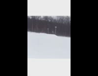 Skier green jacket red pants jumps off ramp and falls down into snow