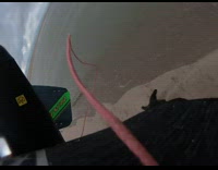 Guy touches beach sand while kitesurfing 