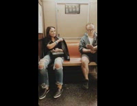 Woman points and fist bumps guy reading his book on subway train
