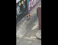 Two women orange sweater dance graffiti wall