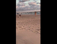 Woman brown jacket sideward arms beach sunset
