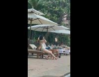 Two women in bikini sits on the poolside bed