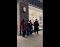 Victorian carolers serenades people walking outside store