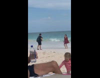 Girl wearing a red dress twirls on beach 