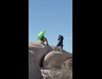 Collab IITW - Man shirtless sits with green umbrella on the rock