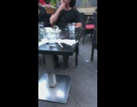 Guy does bottle cap challenge with glass bottle and break glass cups at outdoor restaurant patio