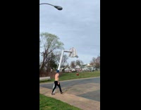 Man shirtless bounces ball on the lamppost and shoots it