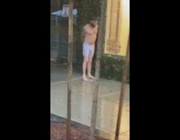 Guy washes body rain sidewalk white shorts 