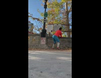 Girl in orange and blue workout clothes twerks on sidewalk 