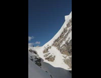 Guy on snowboard jumps over mountain gap