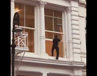 Guy steps through open window to clean it