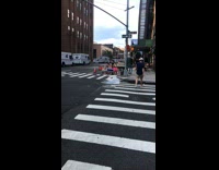 Two women sit in pop up chairs with blue and pink kiddie pools while fire hydrant leaks