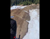 Three people ski downhill with little snow