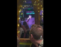 Older man up on stage singing karaoke in restaurant