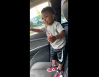 Little boy rolls car window down waves 