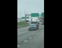 Car being towed by a truck is rocking back and forth on the freeway 
