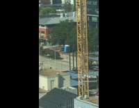 Crane carrying blue porta potty in the air