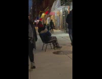 Guy sits on sidewalk chair 