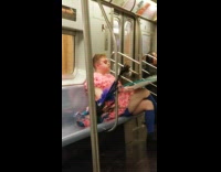 Guy with pink flower dress and make up eats box of pizza on subway train