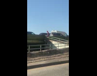 Spiderman sitting on railing waves at cars