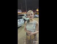 Woman in parking lot with a wild bird perched on her shoulder 
