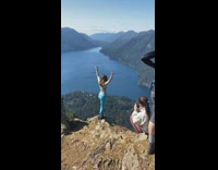 Woman blue leggings stand mountain cliff lake