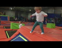 Little boy jumps down trampoline and falls down in slow motion
