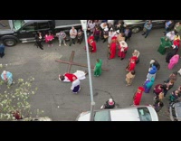 Reenactment, man dressed as Jesus lays on the street with crucifix while followers crowd around him
