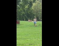 Shirtless guy walks through park with green hair and white shorts