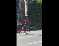 Guy in spiderman outfit standing on bike in street