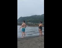 Man in blue shorts flexes back muscles at the beach
