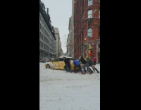 Group of people trying to push a taxi stuck in the snow 