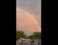 Rainbow arch over parking lot sunset car