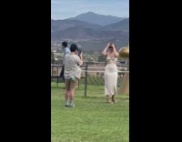 Woman in beige dress poses in front of the golden hand