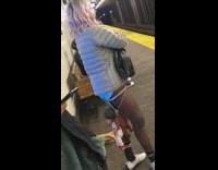 Woman with no pants ties baby dolls around her hips and waits for subway train