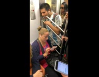 Man blue soccer jersey shirt bites metal rail handle on subway train