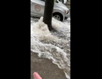 Pipe burst floods street with water pink jacket
