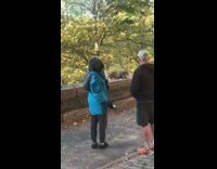 Guy lady watch three raccoons eat food 