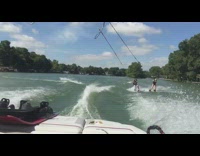 Guy rides water skis and crashes into another water skier 
