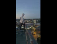Man in Hoodie Shouts on Rooftop of Building
