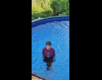 Boy red shirt stands in the pool stare at filmer