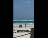 three girls beach shore red shorts seaweed 