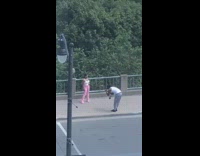 Guy kneels sidewalk photographs girl pink pants 
