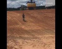 Little boy rides bicycle down dirt hill